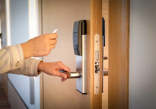 A person unlocks a hotel room door with a keycard