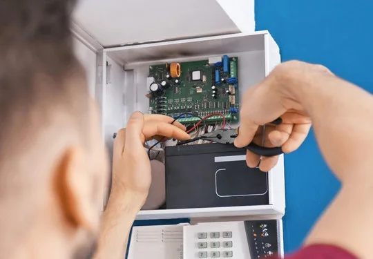 A technician repairs the electronic system for a commercial safe