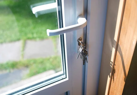 A glass door with keys sitting in the lock