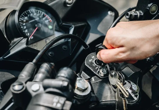 A hand inserts a key into a motorcycle