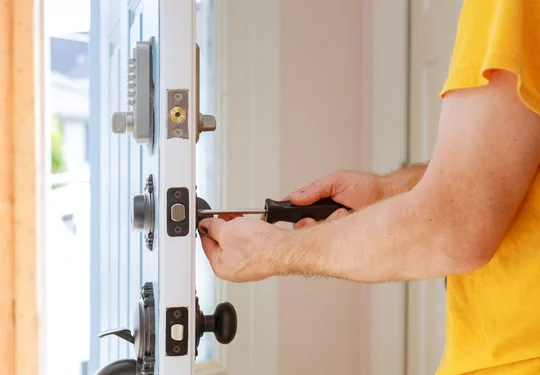 A man installs a new lock into a door