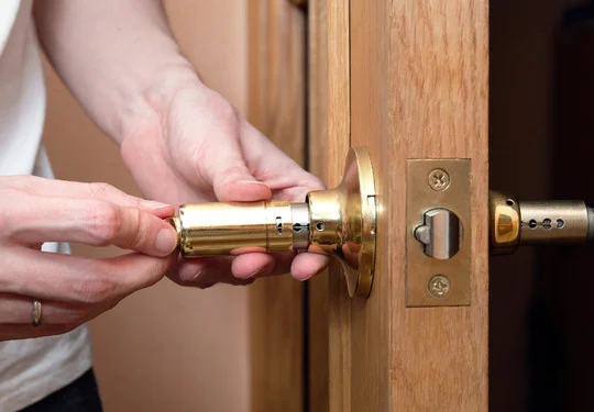 A person changes the lock mechanism on a door
