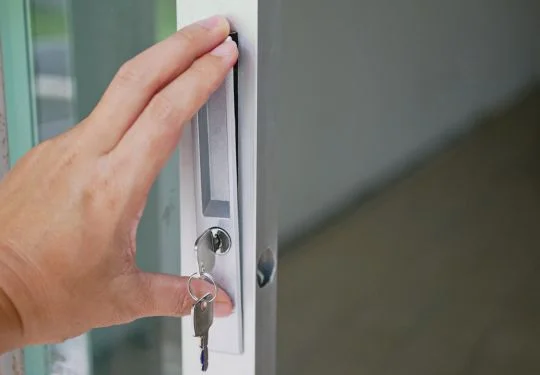 A person installs a new lock on a sliding glass door